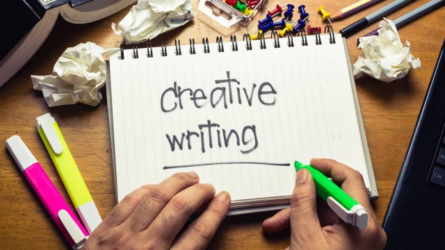 Le mani di una persona destrorsa. Scrive su un blocco "creative writing"