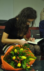 Lara Aversano mentre scrive una dedica per un lettore su una copia del suo libro "Punti senza fine"